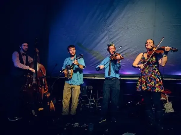 Four musicians playing on stage, with moody lighting